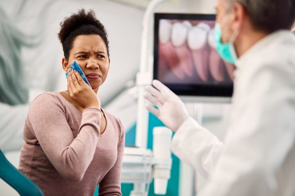 medium shot of an adult woman holding an icepack at Perimeter Dental Group, receiving treatment for infected tooth pain.